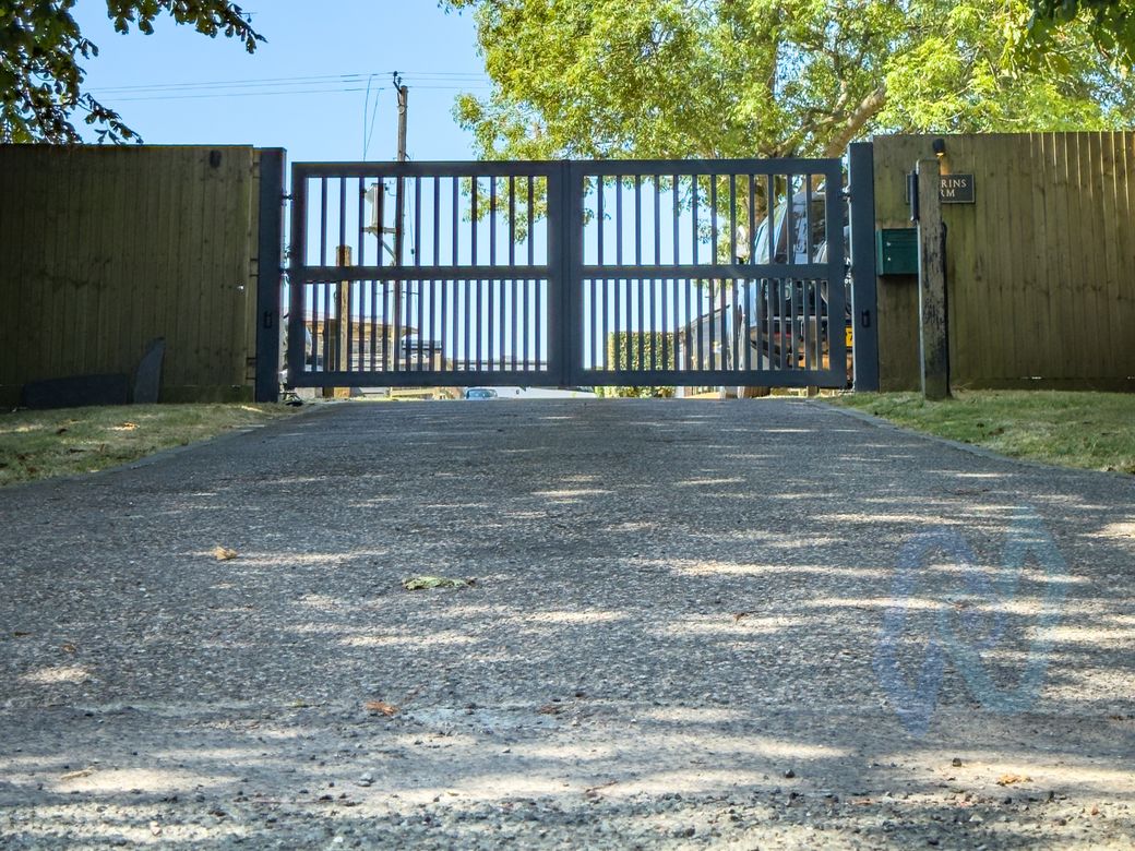 Grey AliGates aluminium swing gates closed across a gravel driveway in Folkestone
