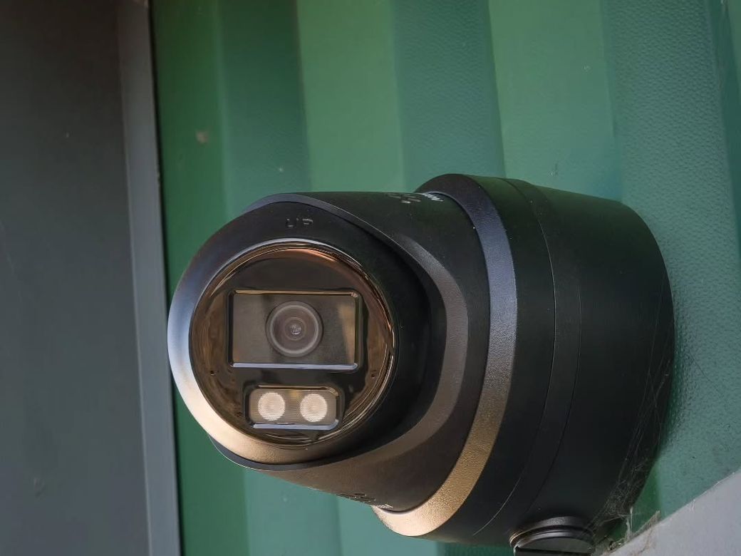 Hikvision colour turret camera with built-in lights on green cladding at a self storage facility